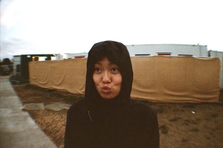 A woman in a black hood pulls a face by the fence