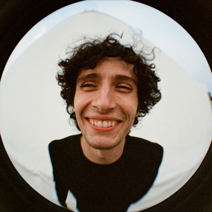 Fisheye portrait: a curly-haired man grinning