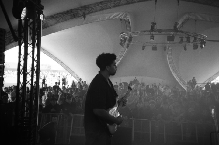A guitarist on stage under the tent, in black and white