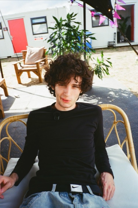 A curly-haired man in a wicker chair