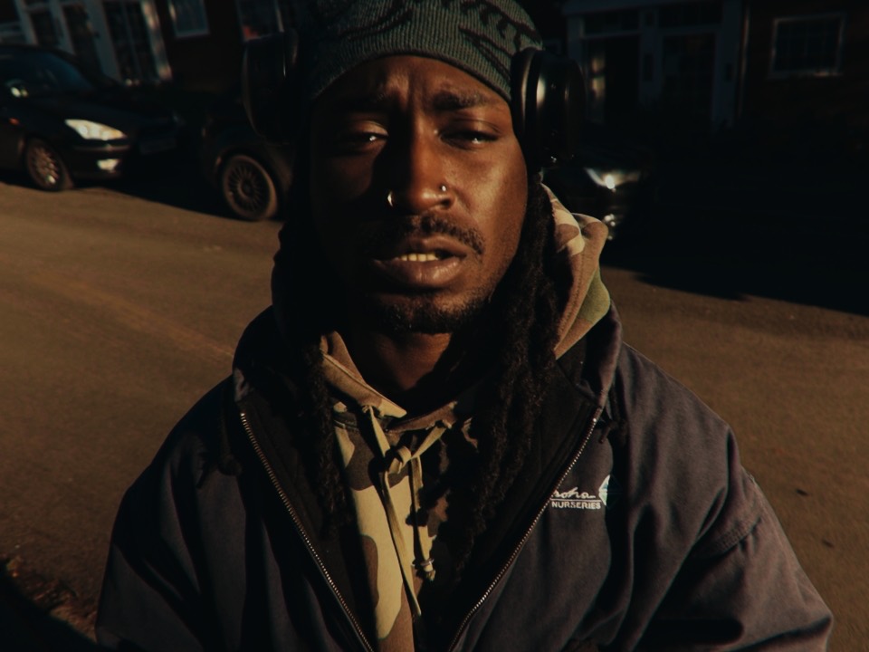 Still from Wali: a man in headphones looks into the lens.